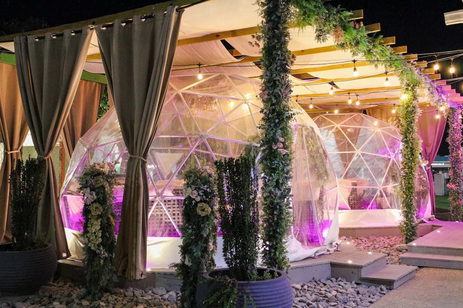 Two igloo lounges outside of The Sweet Spot at night with pink lights.