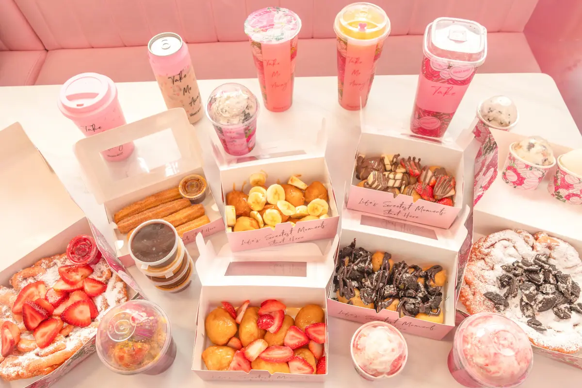 A close-up view of the glass display case showcasing a variety of The Sweet Spot's desserts, including stacked brownies, cookies, charcuterie boards, and milkshakes